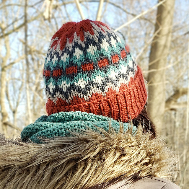 A woman seen from behind wearing a thick knit hat with a colourwork motif.