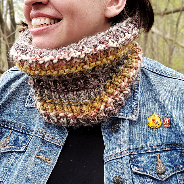 A woman wearing a chunky, multi-coloured, textured cowl.