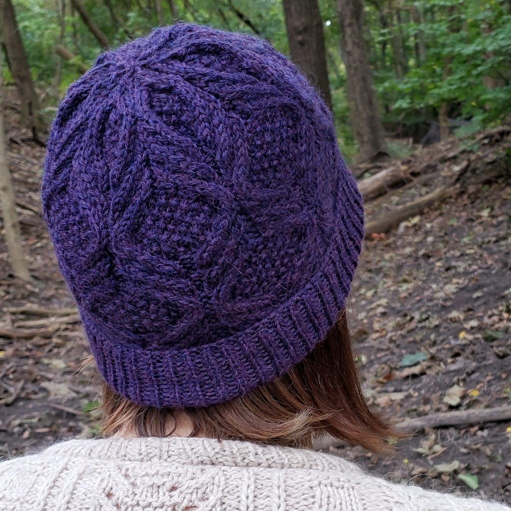A woman wearing a purple cabled toque.