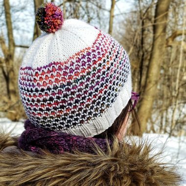 View of a winter hat from behind. Hat features an all over fish-scale type pattern.