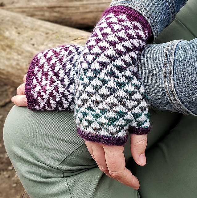A woman wearing a pair of fingerless mitts. Her arms are crossed at the wrist and the mitts feature a triangle motif.